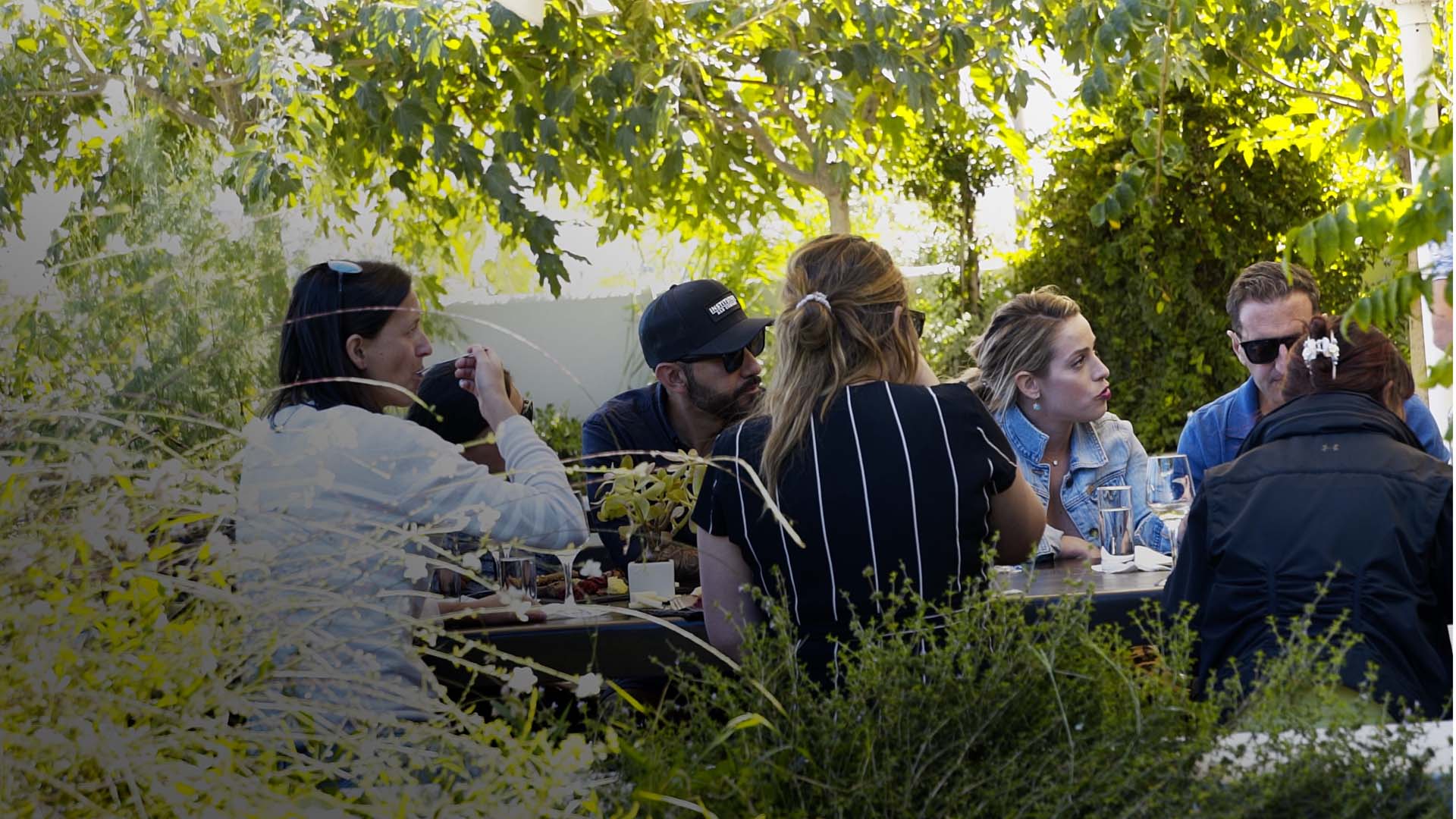Guests at a shaded table tasting wines at a Santorini winery